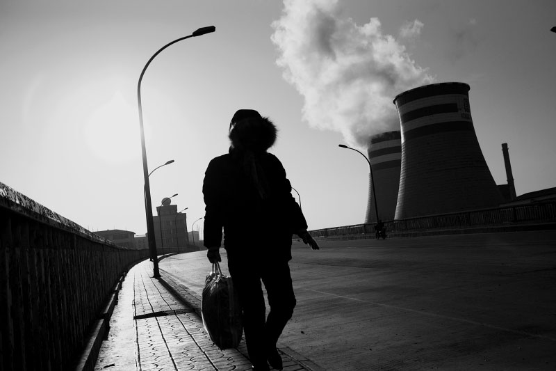 A woman walks near coal burning power plants in Jixi, a coal industrial town, near the Russian border. Coal is still a primary source for power, heating and cooking fuel in China, despite the environmental health hazards.