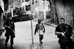 A young female resident in favela Mangueira passes near military police forces, who are in duty for the operation to capture mafia-like gang members of Comando Vermelho. May 2007.