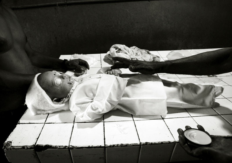 At a funeral home in Anuradhpuraq, North Sri Lanka, funeral workers care a child victim of the June 15 bus attack to prepare for mass burial. The attack was the biggest tragedy since the 2002 ceasefire agreement, although it has nearly been breached for the last six months. The Sri Lankan government accuses LTTE of the terror, but the Tamil political organization denies the claim. And the situation just seems to be at the brink of the restart of war. Sri Lanka, June 16, 2006.