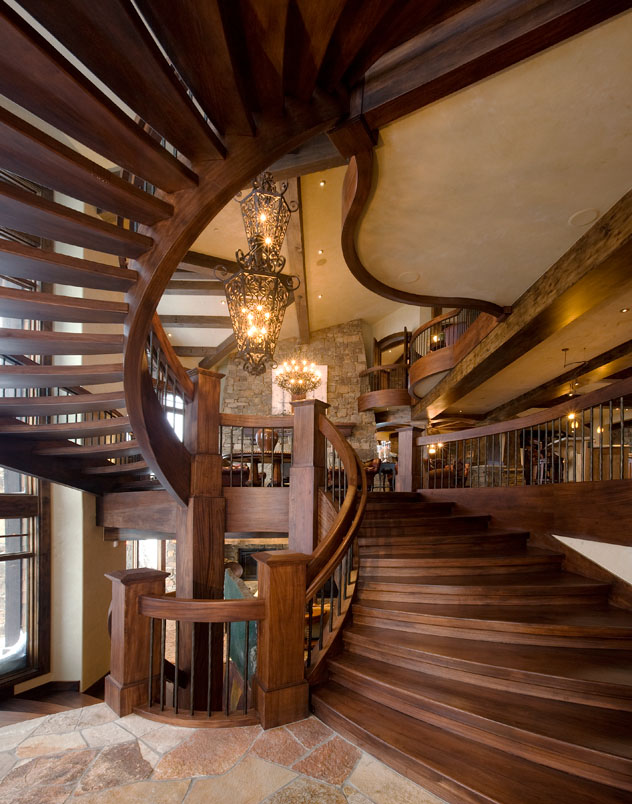 Interior second level view of wooden spiral staircase with tiled floor and wooden railing