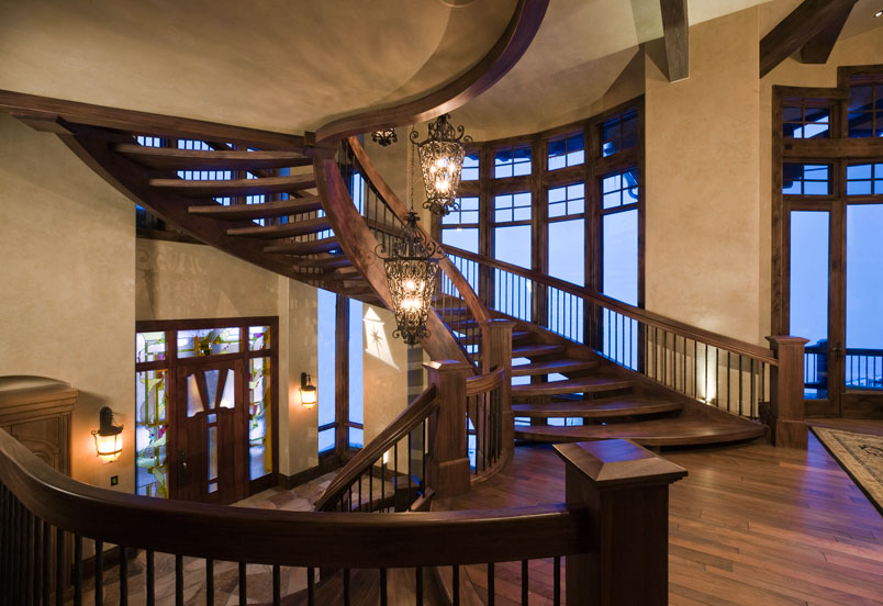 Interior second level view of wooden stairwell with wooden flooring, hand railing and chandalier