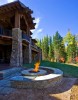 Exterior backyard view of firepit, green grass, and stone veneer