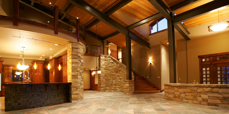 Interior view by front entrance with tiled floor and stone veneer on wooden stairwell 