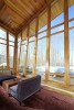 Interior curved glass windows with wooden framing and view of backyard with seating area 