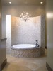 Interior master bathroom with curved stone tile walls aligning bathtub with chandalier
