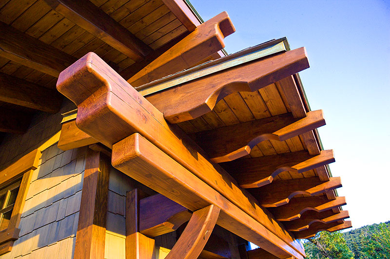 Exterior low angle view of overhanging roof with wooden structual beams and columns. 