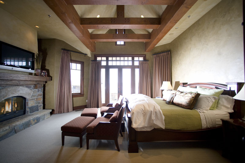 Interior guest bedroom with high ceiling, tv, and fireplace 