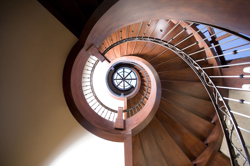 Interior bottom view of downward wooden spiral staircase. 