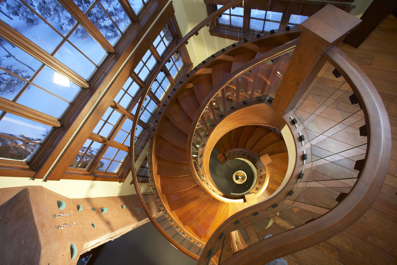Interior upper level view of wooden downward spiral staircase 