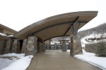 Exterior driveway view of winter porte cochere and four door garage with stone veneer structual columns 