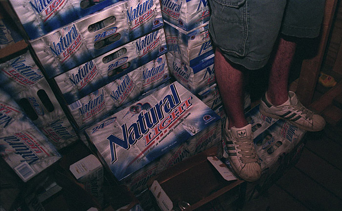 Rocco Tissone stands on a mountain of beer behind the bar at the Theta Chi house during a house party.