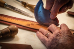 Ray Stokes, an excellent leather craftsman with old, but skilled hands, uses a semi-circular leather cutting knife on a cheek piece for a bridal commissioned by a surgeon from Colorado.
