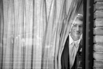 Brandon peeks out as he's sequestered in the room before the ceremony with his groomsmen. Ceremony at Our Saviour Catholic Church, Jacksonville. Wedding photography by Tiffany & Steve Warmowski.