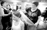 Amanda's mom fastens the veil as Amanda and her bridesmaids get ready at A Hair Company beauty salon in Jacksonville. Wedding photography by Steve & Tiffany Warmowski.