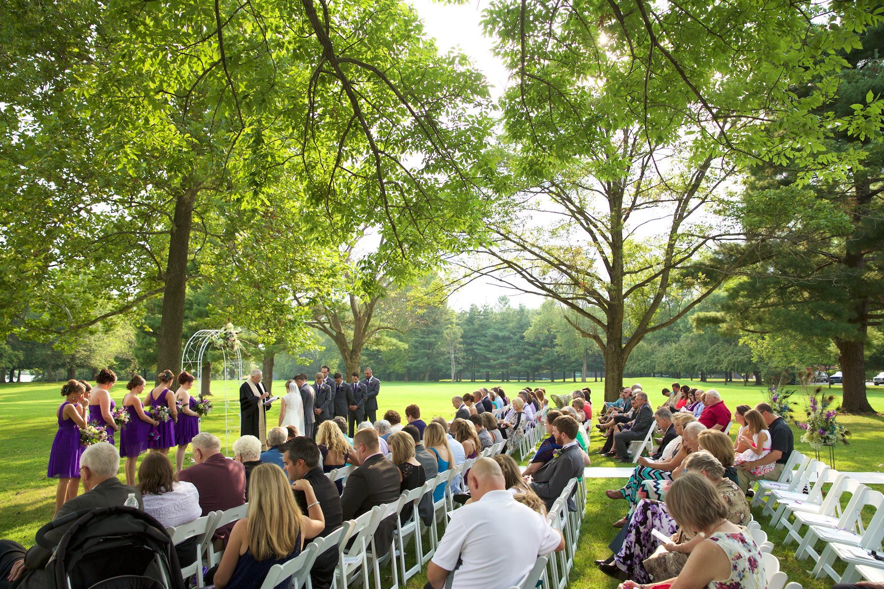 Outdoor wedding ceremony beneath the trees at the Jacksonville Illinois Country Club. Wedding photography by Steve & Tiffany Warmowski.