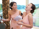Emi's sisters laugh during their toast and speech, wedding at Geneva National Golf Club in Lake Geneva, Wisconsin. Wedding photography by Steve & Tiffany Warmowski.