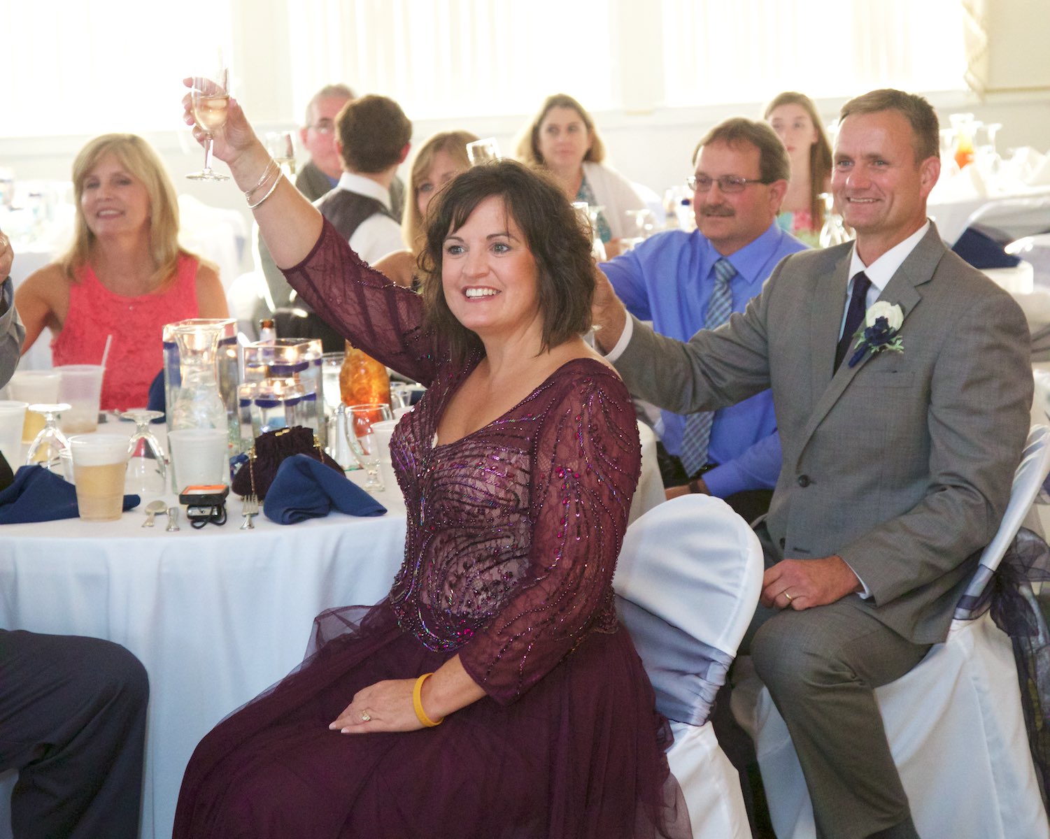 Family and friends raise their glasses for toast, wedding reception at Hamilton's 110 North East, Jacksonville, Illinois. Wedding photography by Steve & Tiffany Warmowski.