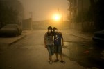 The dust smells like chalk. Heavy and still, the air is orange-tinted. Breathable until it hits your chest, causing a stuttering cough.In the Karrada neighborhood of Baghdad, Hussein Abbas, 10, and Zaid Alaa, 12, head first to a pharmacy for surgical masks. Cousins, but more like brothers. Inseparable best friends, looking for any opportunity to go outside, even during dust storms.Kicking rocks and avoiding puddles of sewage, they have been sent to find a nurse who lives in an apartment a few blocks away. Zaid's sister is sick with the flu and needs medicine.At a maze-like checkpoint for cars, an Iraqi guard ruffles Zaid's dust-grayed hair. From there, the boys can see an abandoned house with balconies torn like twisted metal combs. Three years ago, the windows in Hussein's home were shattered by the force of two suicide bombs that exploded, minutes apart, a few houses down from where he lives.Zaid lived in a different neighborhood at the time. A Sunni group took his home, he says, and now his family lives here in Karrada, a largely Shiite neighborhood. The move was a good thing, Hussein says. His cousin is now his neighbor.Farther down their cluttered, dead-end street, they pass through a tunnel of blast walls. In adrenaline-rushed voices, Zaid and Hussein brag about their favorite players on Iraq's national soccer team, Younis Mahmoud and Hawar Mulla Mohammed.The street is brown, even without the dust. Trash provides the only color. The storm is getting worse. In 10 steps, people disappear into the thickening air.The boys approach the apartment building and realize the streetlights are on. Their skinny legs begin to move faster, up the steps. Hussein's parents have rules, strictly enforced since the double bombing. They must stay in the neighborhood, never walk alone and always come home before dark.