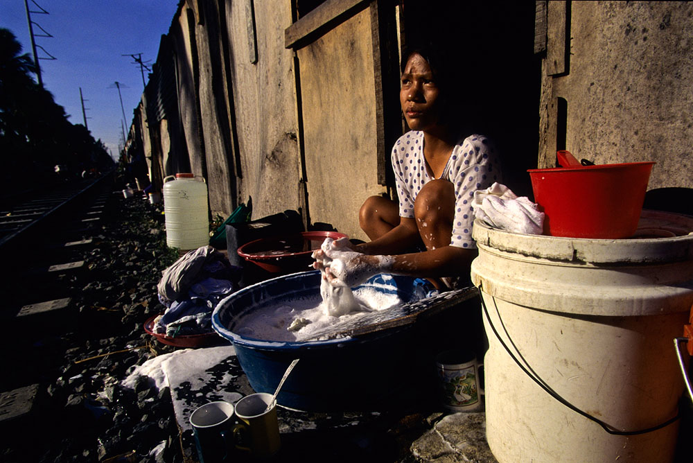 A woman washes her dishes outside her home in Manila, Philippines.