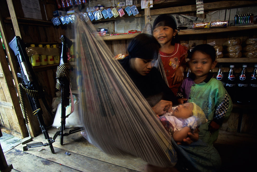 A woman shopkeeper tends to her baby as her other children look on in a Abu Sayyaf camp on the muslim island of Mindanao, Philippines.