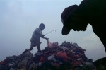 A boy and his father look through the trash for recyclable goods at the Payatas.