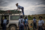 May 4, 2018: KANENGUERERE, ANGOLA - HALO deminer Ana Bimbi Dumbo climbs on the roof of their landrover to start unloading equipment to start their working day in Kanenguerere.  The area was mined during the civil war by government forces to protect the nearby railway line that can be seen in the background, as well as various troop positions. It is currently used by roughly 170 people including village residents and nomadic herders - many of whom are young children - who pass through uncleared land every day. 