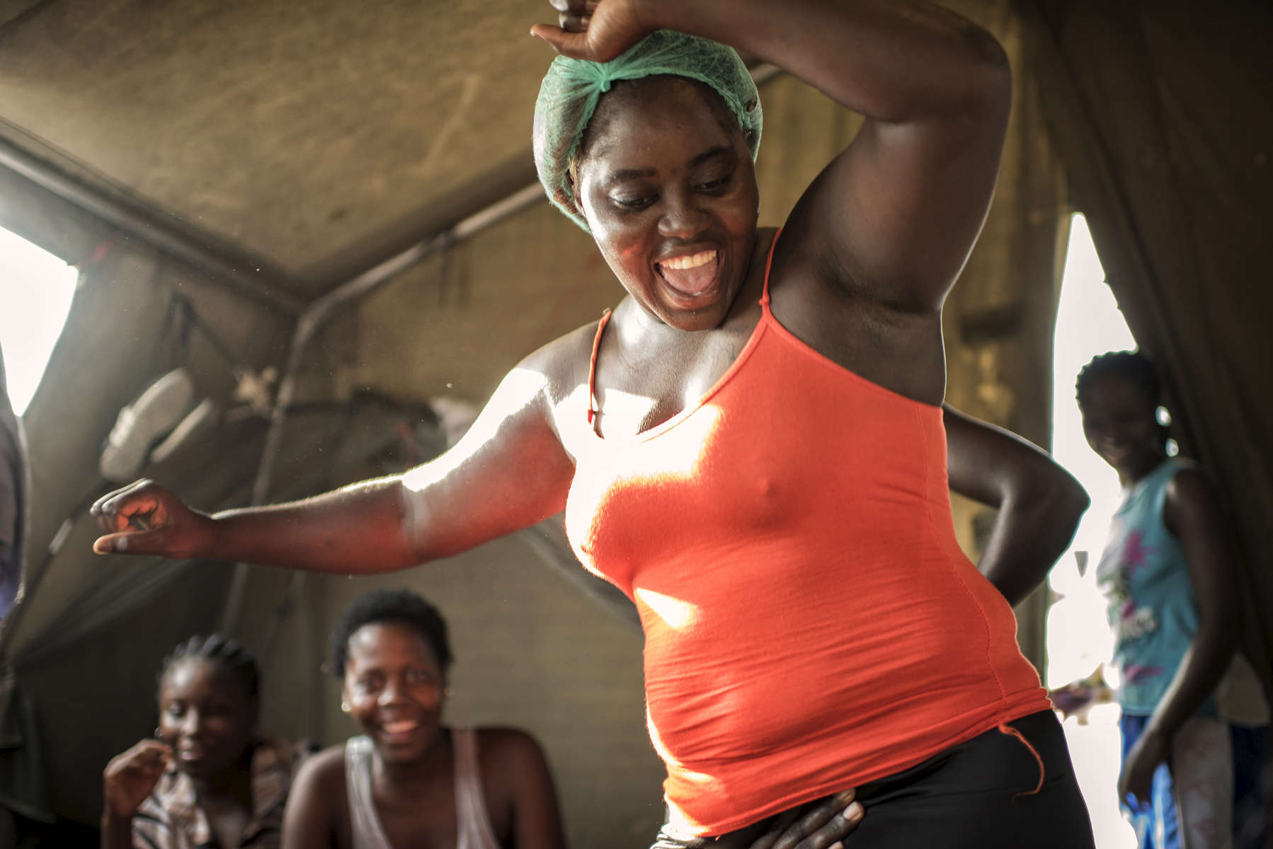 May 3, 2018: KANENGUERERE, ANGOLA - HALO deminer Laurinda Capembe dances in her tent after a full day's  work clearing anti-personnel mines in Kanenguerere.  The area was mined during the civil war by government forces to protect the nearby railway line that can be seen in the background, as well as various troop positions. It is currently used by roughly 170 people including village residents and nomadic herders - many of whom are young children - who pass through uncleared land every day. 