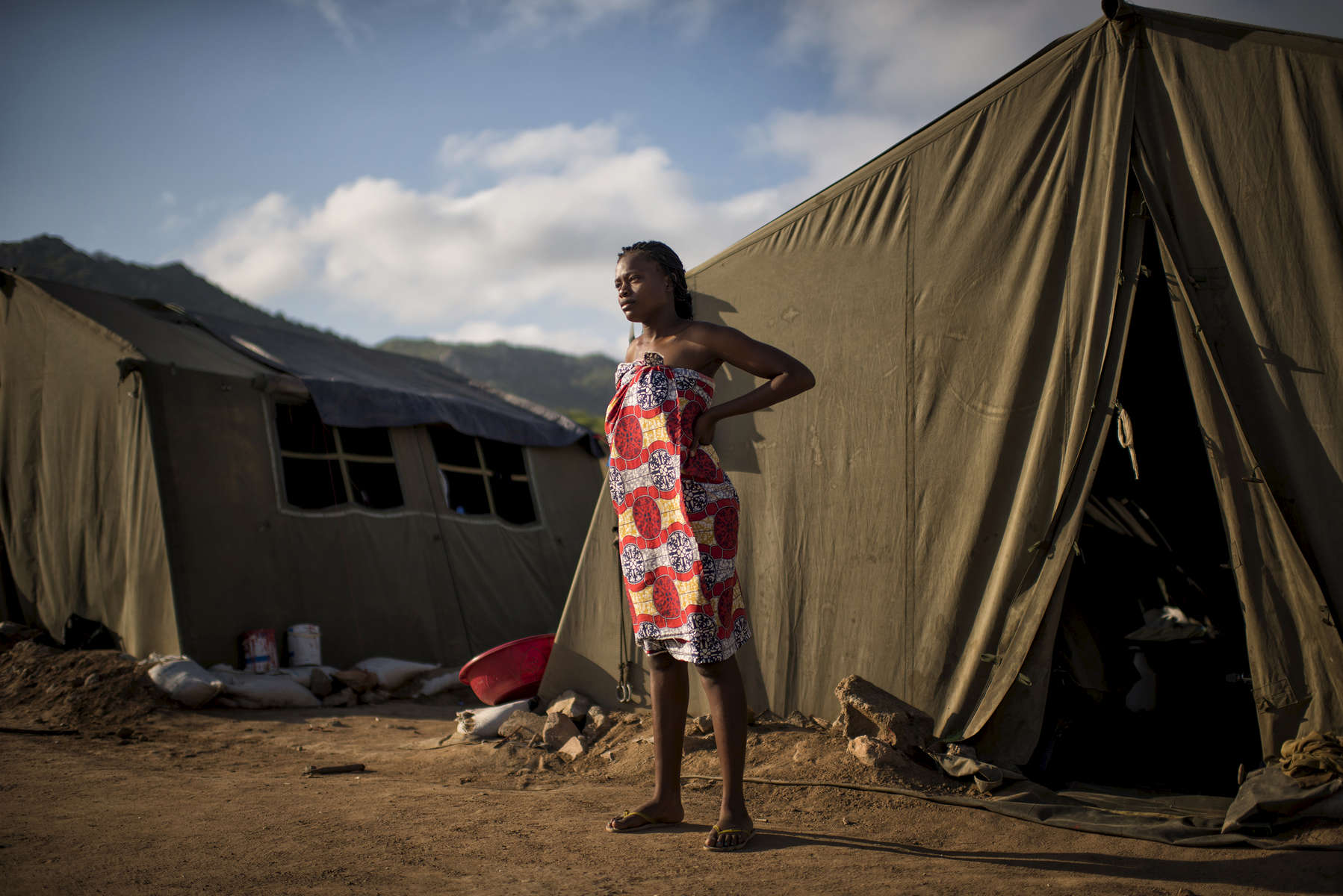 May 6, 2018: KANENGUERERE, ANGOLA -HALO deminer Rosalina Loth stands in front of her tent on Sunday morning. The HALO team has Sundays off, so the day is spent going to church, relaxing, and getting caught up on work. These deminers are working under extremely difficult circumstances in Kanenguerere.  Not only is extremely hot - with snakes and scorpions common - but much of the mined area is on the side of an extremely steep hill, making every step dangerous. The area was mined during the civil war by government forces to protect the nearby railway line that can be seen in the background, as well as various troop positions. It is currently used by roughly 170 people including village residents and nomadic herders - many of whom are young children - who pass through uncleared land every day. 