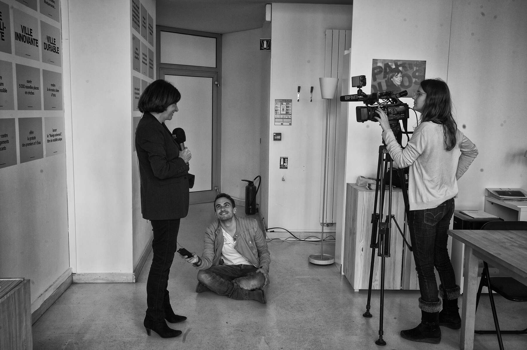 March 16, 2014.  PARIS, FRANCE- Press liaison Hervé Marro holds up a recorder as mayoral candidate Anne Hidalgo does a television interview in her campaign's headquarters in Paris' Bastille neighborhood.   For the first time in France's history, Paris will have a woman as a mayor - either Socialist Anne Hidalgo or Center-Right Nathalie Kosciusko-Morizet.  Photo by Scout Tufankjian