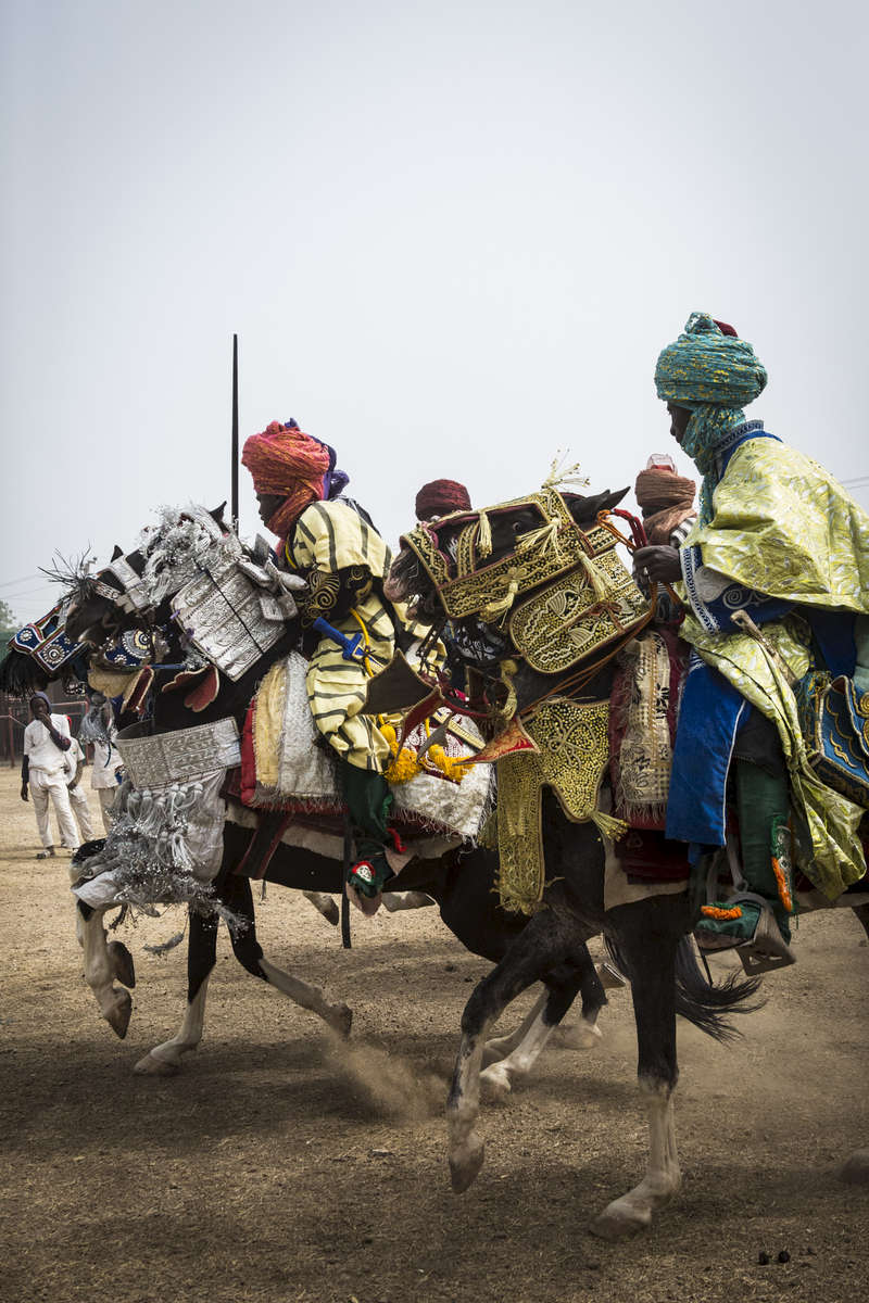 Members of the Emir of Kano, Muhammed Sanusi II's, court race their horses outside the palace in Kano, Nigeria