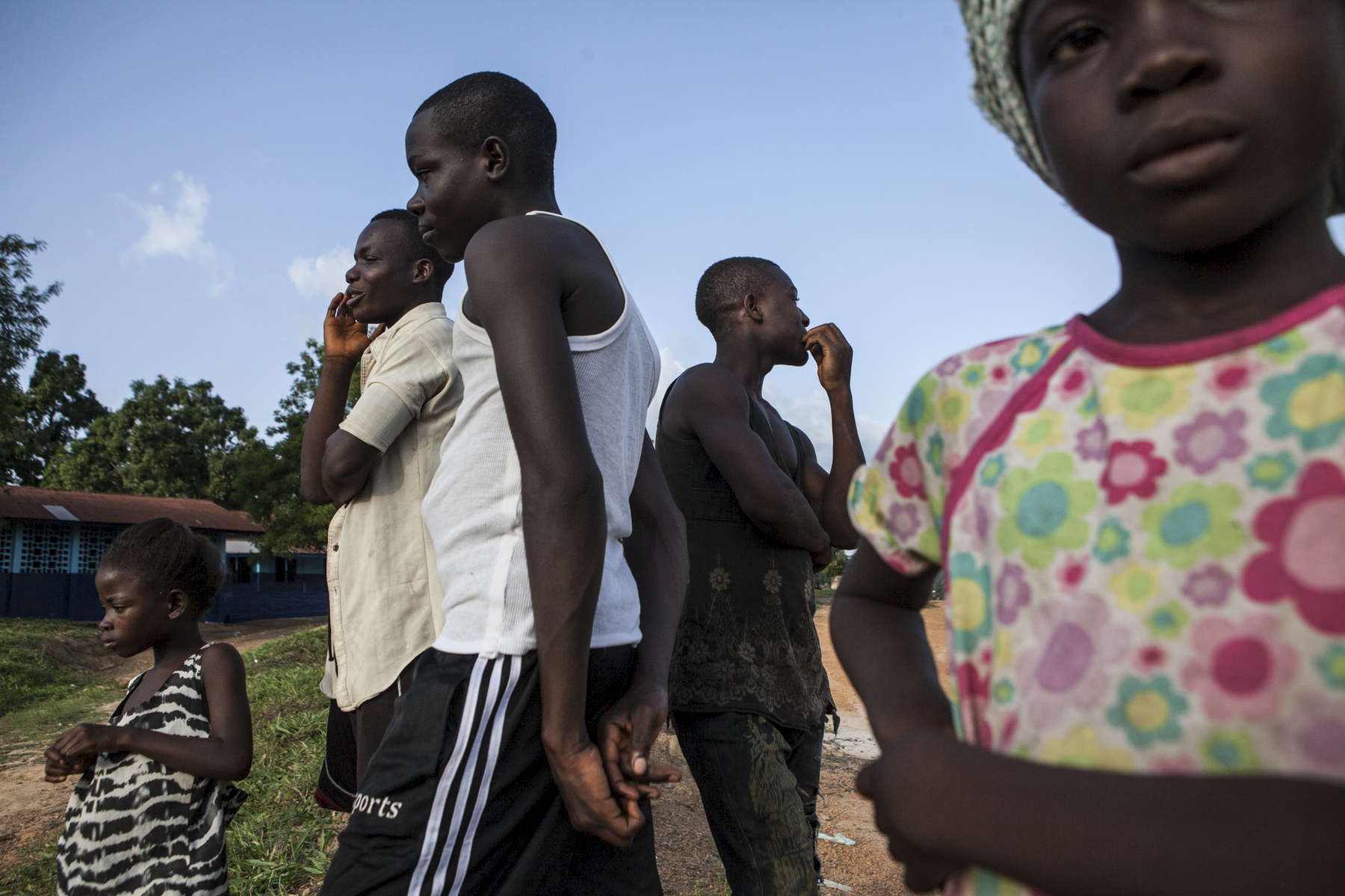 Maxwell Zekeh, 16, (second from left) stands with his siblings outside of his Bridge supported school in Bong County, Liberia