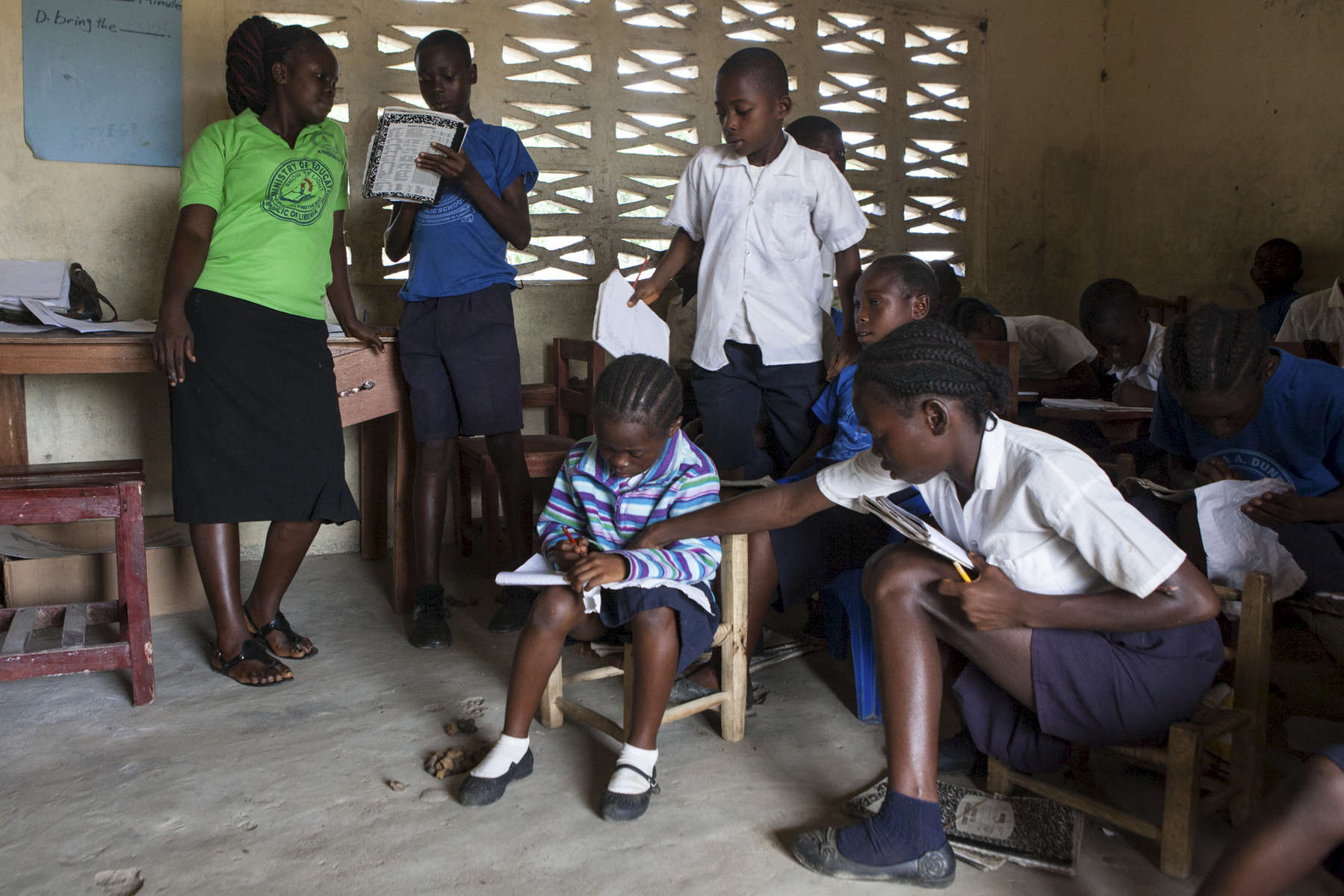 A teacher advises her students in her K2 math class at the Cecilia A Dunbar Public School in Freeman Reserve, Liberia 