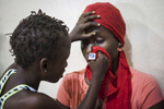 Aminata Conteh, 8, carefully wipes around the eye of a fellow ebola survivor at the Kissy United Methodist Church Eye Hospital in Freetown, Sierra Leone.