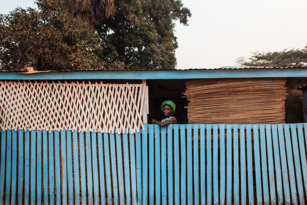 A young woman looks out from behind a fence in Bangui, Central African Republic