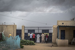 Men stand at the gate watching as others push a car free from the sand at an internment camp for ex-Boko Haram combatants in Goudoumaria, Niger, August 2018.