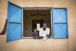 Abukhar, 45, and his son Abukhar, 6, look out the window of their dormitory room at an internment camp for ex-Boko Haram combatants in Goudoumaria, Niger, August 2018. Yassine and his family have been at the camp for 8 months.