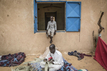 Ari,12, sits in the window as Abukar Bulama, 45 weaves a straw mat at an internment camp for ex-Boko Haram combatants in Goudoumaria, Niger August 2018. 