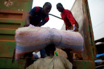 Men unload sacks of cocoa beans in San Pedro, Ivory Coast.  The San Pedro Port is the primary point for exporting raw materials, especially cocoa, out of the country. At times, cocoa sacks are emptied into vacuum containers as a method of transport overseas.