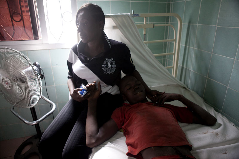 Mary-Louise Diby holds her 21 year old nephew who was shot in the leg, in a clinic in Treichville, a suburb of Abidjan, Ivory Coast on Tuesday, March 8, 2011. Women marched through the streets of Abidjan today mourning the deaths of seven women killed last week by security forces loyal to Laurent Gbagbo. In Treichville, after finishing prayers (both Christian and Muslim) the marching women encountered the {quote}Compagnies Republicaines de Securité{quote} (CRS), special riot police loyal to Laurent Gbagbo. Its reported that the neighborhood youth guard stood in a line between the women and the CRS to protect the women when the CRS opened fire. At least four were killed including one woman and unknown number were injured.