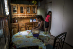 Nejapa, El Salvador- Priscilla Perez, 32, with her niece Aixa Ortiz, 9, make lunch at their home in San Jeronimo Los Planes, Nejapa, El Salvador June 2018. Water is collected during the rainy season in the communal tank and sold for 10 cents a jug during the dry season, money raised is used to fund water trucks once the tank runs dry (usually the tank only lasts for two months into the dry season). Unfortunately the roof was lost during a recent hurricane and very little water has been collected since, worrying the Perez family. Nejapa is not only home to a number of bottling plants including Coca Cola and Lactolac, it also lies above one of El Salvador's largest aquifers, feeding neighboring communities and much of San Salvador.The San Antonio River, once a main source of water for Nejapa, has been contaminated by the waste produced by industrial bottling plants since their arrival in 1996. Bio filtration systems were installed but have been broken since 2006. (Jane Hahn)