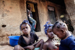 Etienne Ouamouno, 31, watches his daughters Marie, 6, Seyou, 7, and Kane, 2, (L to R) outside their home in Meliandou, Guinea on January 25, 2015. Meliandou is starting point of the Ebola epidemic when toddler Emile Ouamouno was the first to die from the virus in December of 2013. Since then 15 people have died of Ebola in the small village leading 200 people to flee since the start of the epidemic leaving 400 people. What was once a prosperous farming community, most now live in hunger unable to tend to their fields of mainly corn, palm and coffee. 