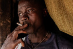 Etienne Ouamouno, 31, smokes a cigarette outside his home in Meliandou, Guinea