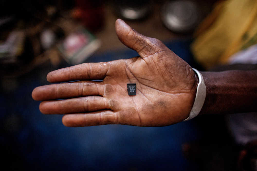 Susso, 38, holds the micro SD card he will use to store the photos he will take on the {quote}back way{quote} journey  to Europe (through the Gambia, Senegal, Mali, Burkina Faso, Niger through the desert to Libya), in his home in Dampha Kunda Village. This will be Susso's third attempt to reach Europe.