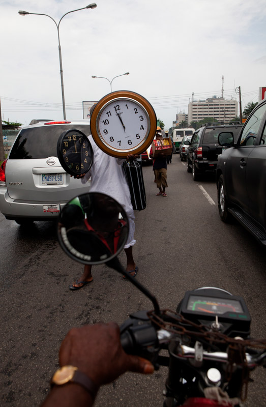 a man sells clocks in traffic in lagos, nigeria