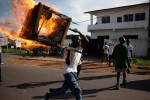 A man carries a burning stand after riots break out during a protest over runoff elections in Monrovia, Liberia