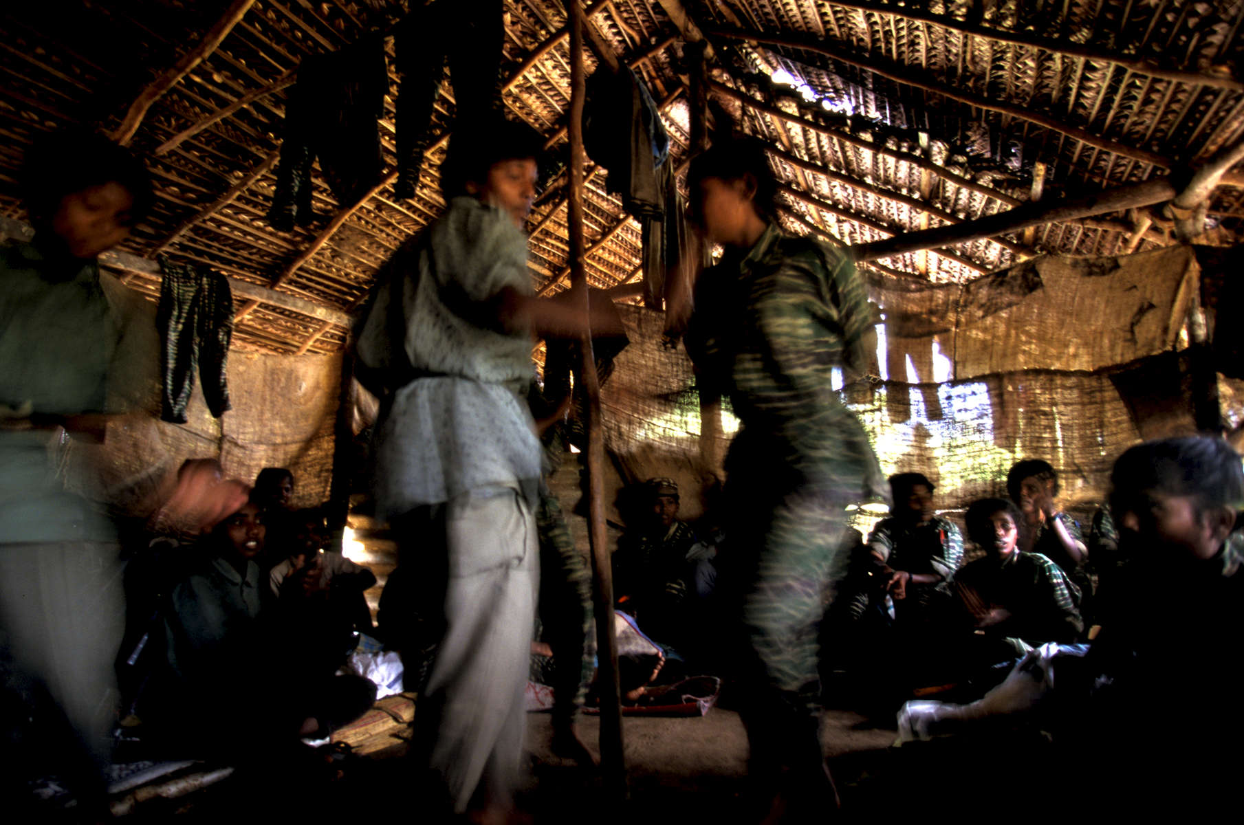 Female cadres of the LTTE singing and dancing to revolutionary songs after military training had been interrupted from a monsoon rainstorm in the northern Vanni region of Sri Lanka. 1998