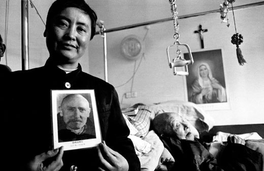 Sister Francis shows a picture of foreign missionary Vincent Lebbe.  Father Lebbe trained the 98-year-old priest in the backgroundHebei province