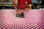 A worker  uses the wooden handle to make color patterns on cotton cloth in the Jaipur cooperative for cotton and carpet production. The colors used are natural and paintings of fabrics are done manually. 