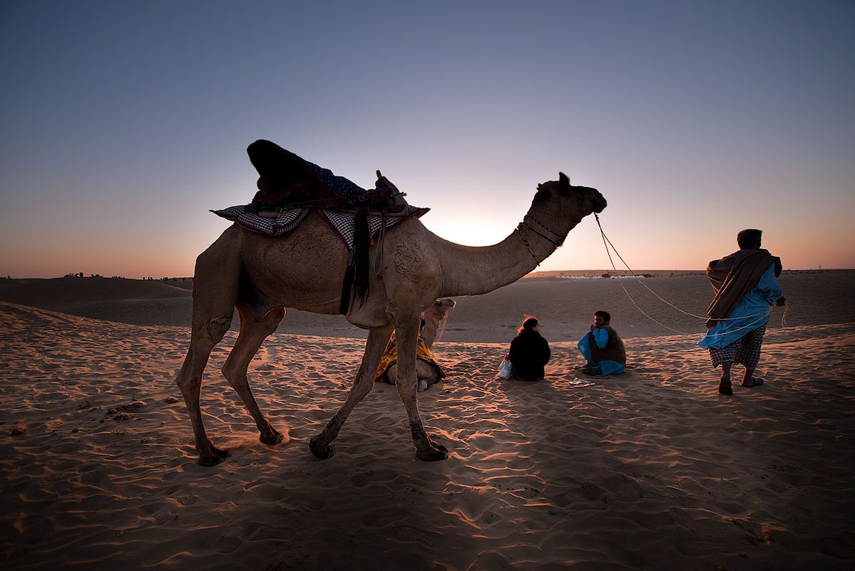 Jaisalmer desert.Doud Khan, a camel handler talks to a tourist while waiting the sunset over the sand dunes in Jaisalmer desert which is the main attraction. 