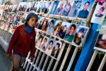 Prishtina, Kosova.A young boy walks by photographs of the missing persons who were never found since the 1999 war. Photographs are displayed by the families of the missing persons and and every year members of the family place flowers nearby. Photographs are displayed since 1999 on the fences of the Government building in Prishtina Kosova 